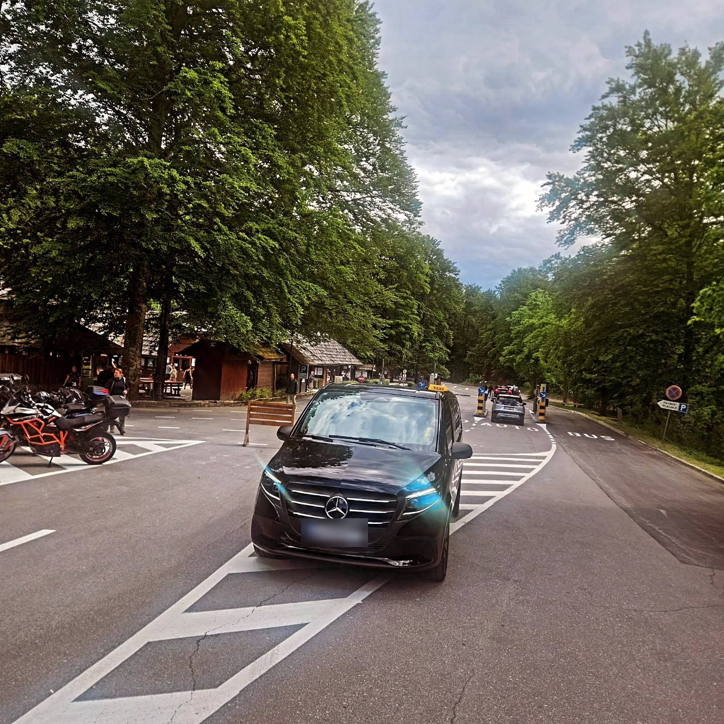 A black van on a tree-lined road at Plitvice Lakes