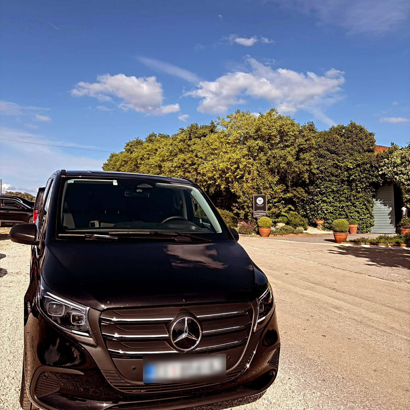 A black passenger van photographed by Atram, seen from the front in sunshine