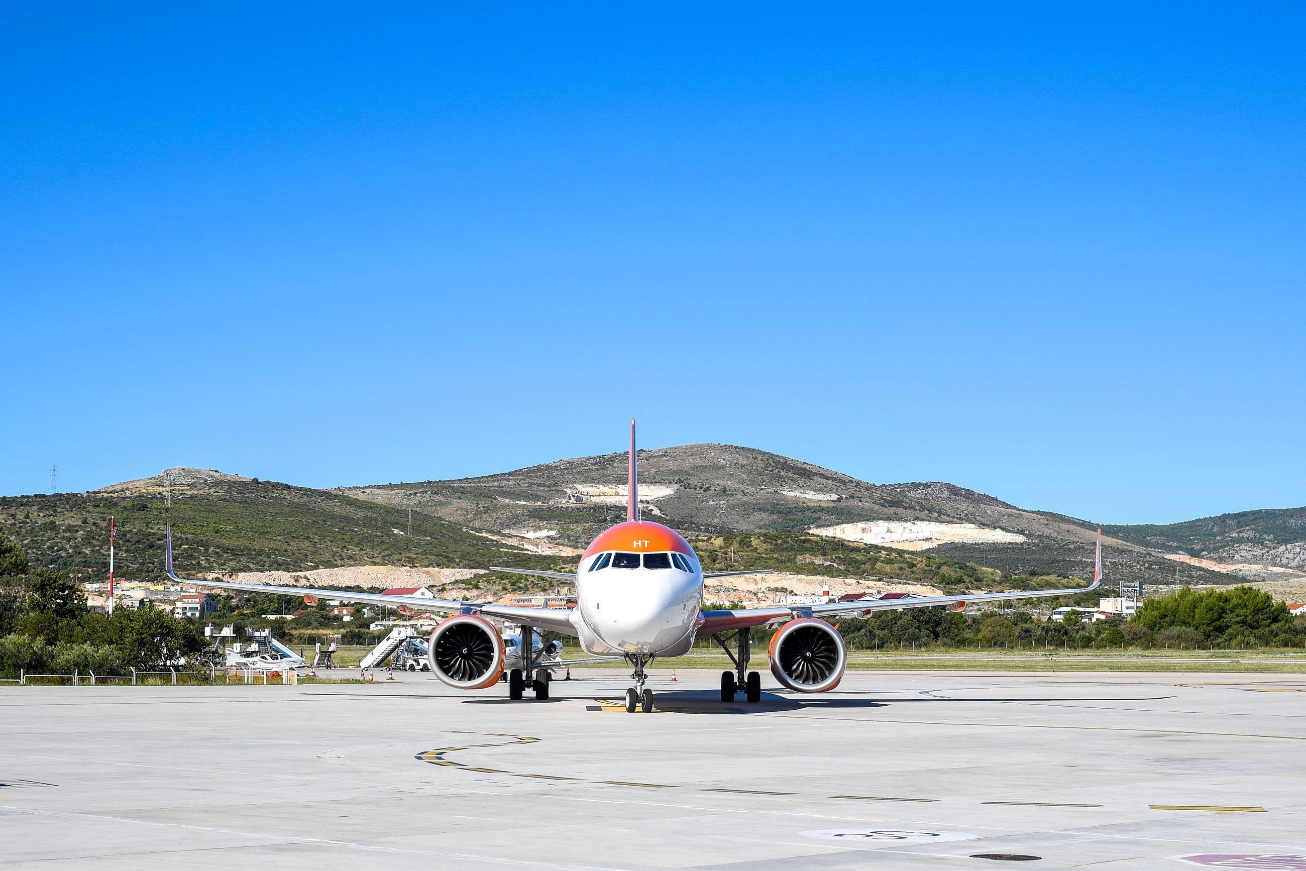 A passenger aircraft on the apron at Split Airport, with the hills behind